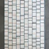 A luxury designer rug featuring a grid of white and light brown textured rectangles on gray.