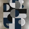 Luxury designer rug with overlapping blue, black, gray, and white geometric shapes on concrete.
