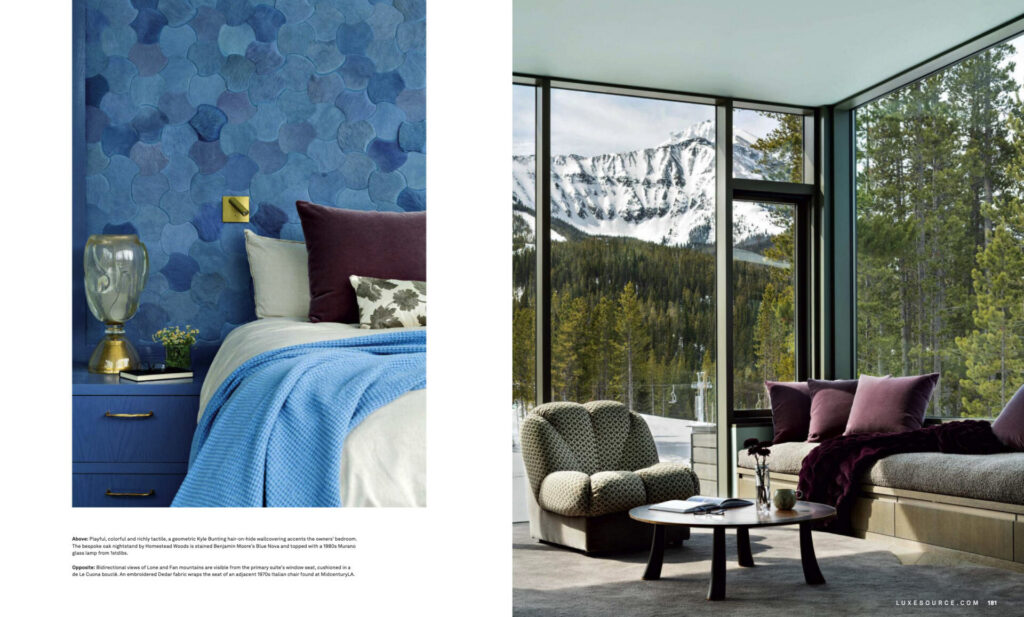 A modern bedroom with blue walls and luxury designer rugs, plus a sitting area with mountain views.