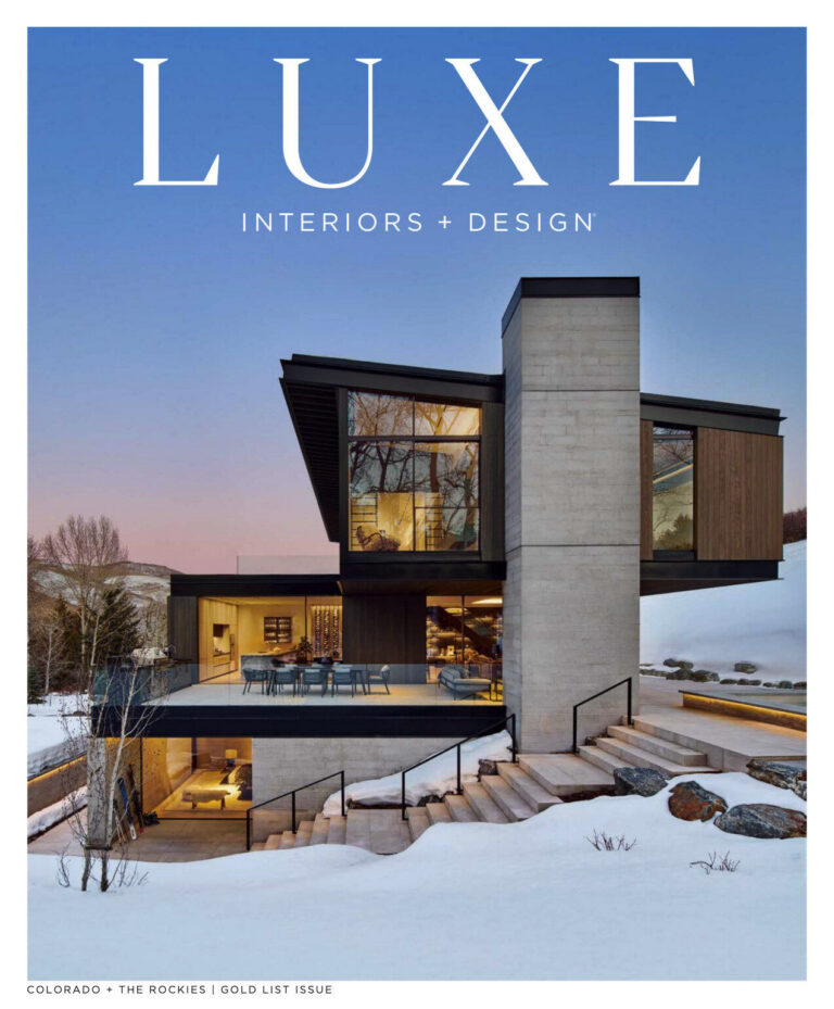 Modern house with glass windows and snowy yard, featuring high end designer rugs inside.