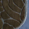 Close-up of a luxury designer rug corner with irregular brown shapes on a gray background, showcased on a blue-gray surface.