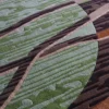 A close-up of a luxury designer rug with green, brown, and tan wood-grain pattern.