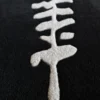 Close-up of a white fish skeleton motif on a textured black luxury custom wool designer rug.