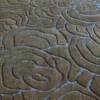 Close-up of a luxury designer rug with brown textured wool, showcasing swirling, raised abstract patterns.