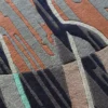 Close-up of a luxury designer rug with abstract gray, brown, black, and green patterns.