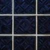 Close-up of a luxury custom rug with a geometric pattern in dark blue and black squares bordered by beige lines.