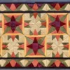 The Fancy Hide 16177 showcases a designer handmade hide rug with a geometric quilt motif in rich hues.