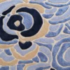 Close-up of a luxury designer rug with textured wool, navy and beige abstract florals, and high-end handmade detailing.