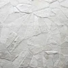 Close-up of a luxury designer rug surface with uneven white texture and geometric patterns.