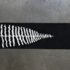 Luxury handmade wool rug, black with a white fern motif and four lines, on concrete.