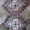 Winterlude Hide 26020 luxury designer rug with geometric arrow and dot motifs in beige, red, green, and black on textured high-end hide.