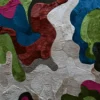 Luxury designer rug with abstract, layered textured shapes in red, green, and beige tones.