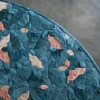 Close-up of the Fez Hide 28129 luxury designer rug, a round handmade hide rug with blue and pink abstract pattern on gray floor.