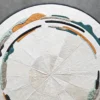 Luxury custom designer rug 27209 in handmade hide, round with abstract teal, ochre, black, and gray patterns on white.