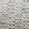 A feature wall with metallic triangle tiles, echoing patterns in luxury designer rugs.