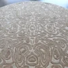 Round beige handmade wool rug with intricate swirling pattern, luxury designer rug.