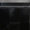 Luxury Custom Hide 28620 black designer rug with white X-edged stitching on gray floor.