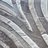 Close-up of luxury designer rug Drift Hide 28893, showing curved segments resembling artisanal animal hide in neutral tones.