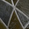 Close-up of a luxury designer hide rug with geometric brown and gray pattern and silver-edged seams.