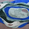 Luxury handmade designer rug with abstract, layered topographic shapes in blue, green, and beige on a brown hide background.