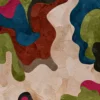 Luxury designer rug with abstract, organic shapes in green, red, blue, and pink tones.