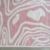 A close-up of Urushi Wool 28585 luxury designer rug with a pink and white abstract, topographic pattern on a gray floor.