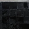 A luxury designer rectangular black Promenade Hide 30151 handmade hide rug with large square sections on a concrete floor.