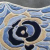 A close-up of the Bloom Silk Wool 30123 luxury designer rug with a textured abstract floral design in blue, beige, and navy on gray.