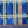 Luxury designer patchwork rug of handmade hide and leather in blue, beige, and brown geometric pattern on wood floor.