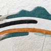 Close-up of a luxury custom designer rug with curved green, black, orange, and cream hide pieces.