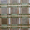 Close-up of a luxury designer rug, handmade hide with green, beige, and brown geometric grid.