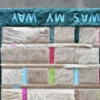 Luxury designer rug featuring beige hide panels, colorful stripes, and bold text border.