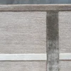 Close-up of a luxury custom handmade wool designer rug, beige with textured intersecting off-white and grayish-brown geometric lines.