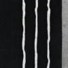 Luxury designer rug: black handmade wool rug with wavy white lines on grey concrete.