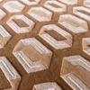 Close-up of a high end designer rug with textured handmade wool, silk accents, and a beige and white hexagon pattern.