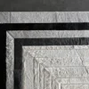 Luxury designer hide rug with gray, black, and white concentric bands on a dark floor.