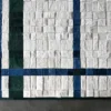 Luxury designer rug with square furry-textured handmade hide tiles, blue and green lines on white, on a grey floor.