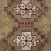 A luxury designer rug with geometric shapes in red, yellow, black, and beige on a textured brown handmade hide backdrop.