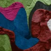Luxury custom designer rug with abstract blue, red, and green patches in a textured, handmade hide finish.