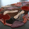 Luxury custom designer rug in abstract hide, red, purple, beige with orange edging.