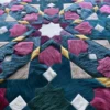 Close-up of a luxury designer rug with a symmetrical, mosaic geometric pattern in teal, pink, yellow, cream, and white Kasbah Hide.