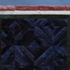 A close-up of a luxury custom designer hide rug with multicolored geometric patchwork and textured borders.