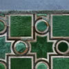 A luxury designer rug features green geometric patterns on gray with tan borders, showcasing high-end handmade quality.