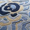 The Bloom Silk Wool 30123 designer rug showcases blue and beige abstract florals in luxurious handmade silk wool, ideal for high end interiors.