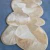 Luxury designer rug with beige and cream organic patchwork on a blue floor, handmade hide rug.