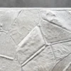 A close-up of the Lexar Hide 15275 luxury designer rug with handmade hide patchwork on a grey concrete floor.
