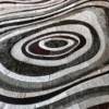 Close-up of a luxury designer rug with textured concentric ovals, reminiscent of handmade hide rugs.