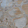 Luxury designer rug with abstract textured surface, gold lines on metallic gray background.