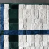 Close-up of a luxury custom designer rug with white, blue, and green fur squares on concrete.