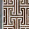 Luxury designer rectangular area rug with brown and white geometric maze on textured fur-like surface, displayed on a gray floor.